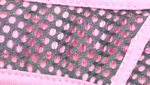 A close‑up photograph shows sport wrap adjustable dog harness fabric in pink. The material appears to be breathable mesh with evenly spaced perforations. The pink mesh is bordered by darker trim, and the texture appears soft and flexible.