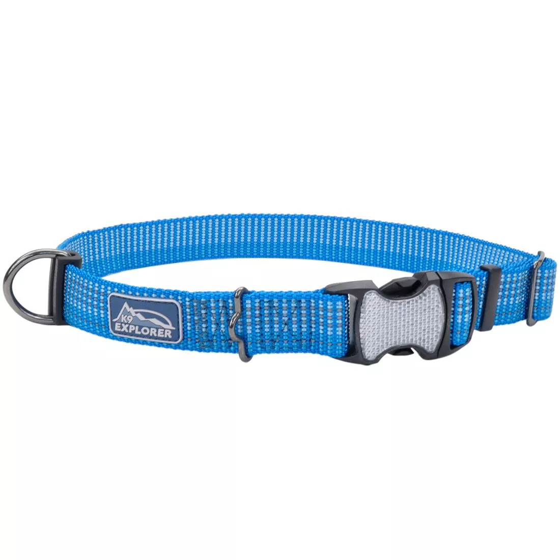 A blue adjustable dog collar is displayed against a white background. The collar is constructed from blue woven nylon with reflective center stitching and black edge trim. A silver metal D‑ring is attached at one end. The collar includes a gray plastic side‑release buckle and a gray plastic adjustment slider. A brand patch is stitched to the strap.