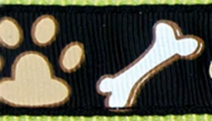 A swatch depicting a dark chocolate‑brown background with a series of tan paw prints and white bone shapes arranged in a repeating horizontal layout. The paw prints are light tan with darker centers, and the bones are white with grey outlines. A narrow border of bright green stitching appears along the top edge, adding a pop of color.