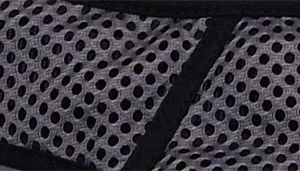 A swatch displays mesh fabric in gray with black accents. The material has a perforated structure with evenly spaced circular holes. A black fabric strip runs diagonally across the mesh, and the surface texture appears soft and breathable.