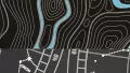 A swatch showing a printed topographic map design on a charcoal‑grey background. Bright blue contour lines curve and ripple across the surface, intersecting with smaller white dashed lines and symbols reminiscent of mapping coordinates. The print includes layered line thicknesses, directional curves, and bold contrast, creating a modern, cartographic aesthetic.