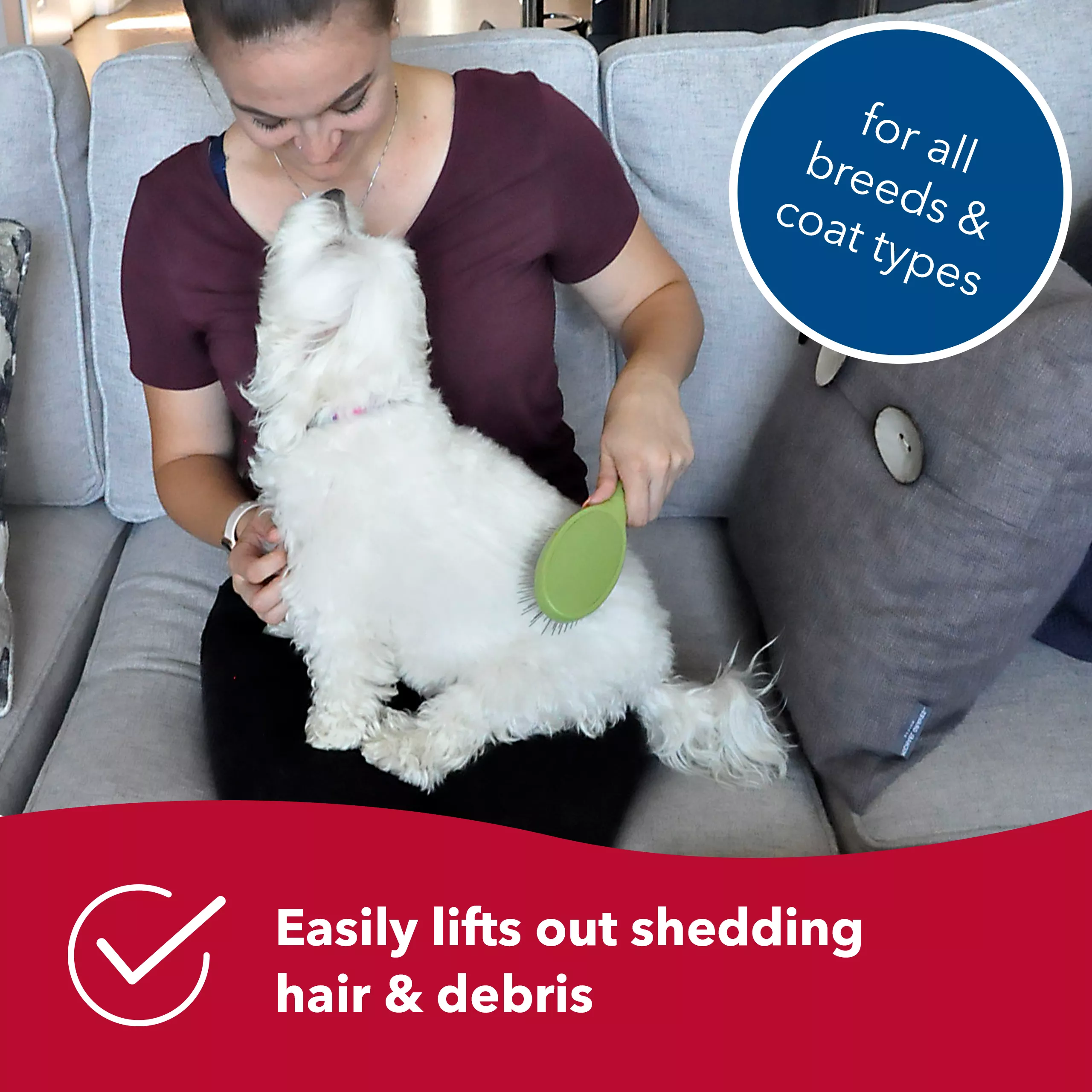 A lifestyle image of a person brushing a white long‑haired dog using a wire pin brush with a plastic handle. A blue circular graphic near the upper right contains the printed text “for all breeds & coat types.” A red banner along the bottom displays a white checkmark icon and the printed text “Easily lifts out shedding hair & debris.”