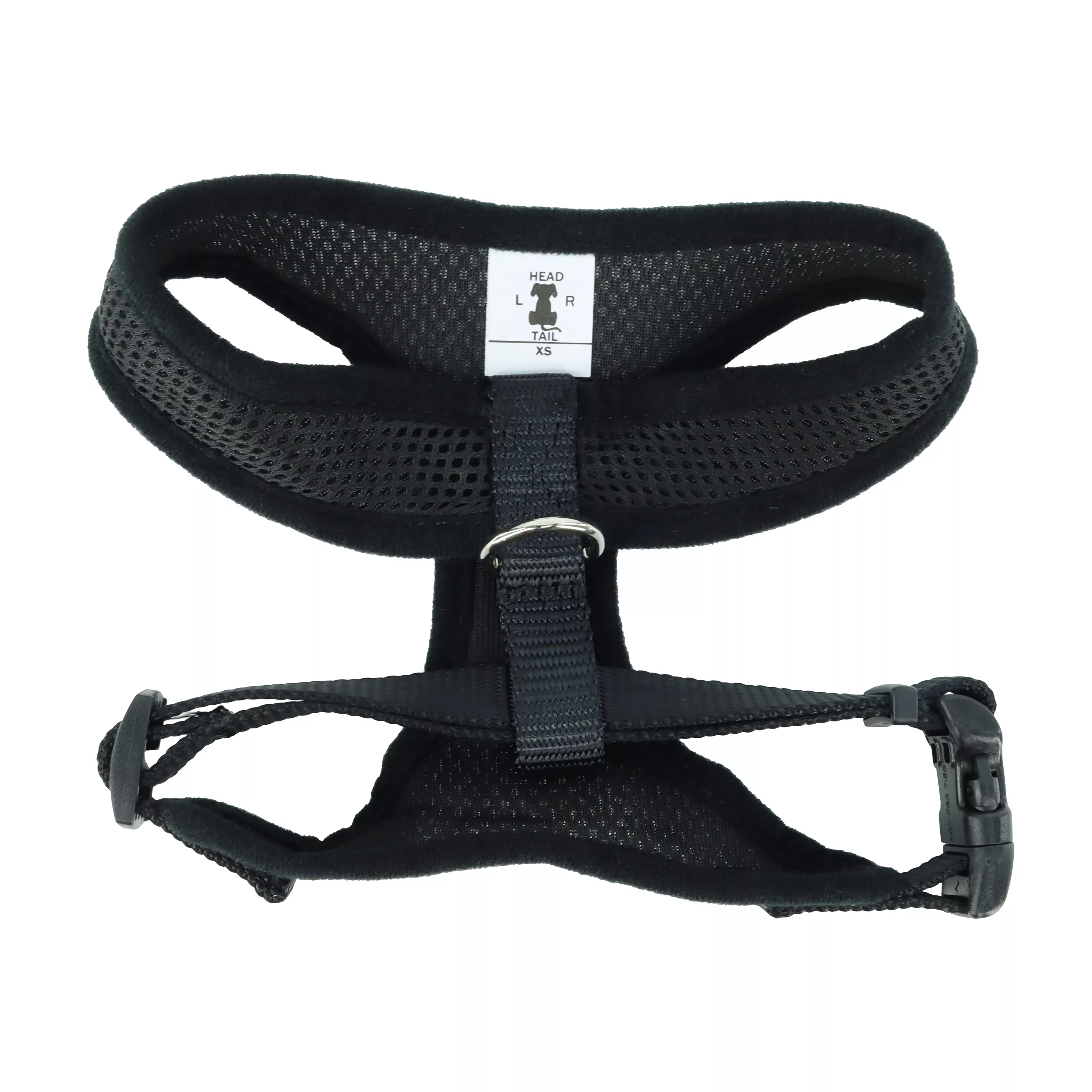 A product‑only image of a black Comfort Soft adjustable mesh dog harness displayed against a white background. The harness features a padded black mesh chest panel with a textured honeycomb pattern and contoured openings for the neck and forelegs. Black woven straps with black plastic adjustment sliders connect the mesh sections. A black plastic side‑release buckle secures the girth strap, and a silver‑tone metal D‑ring is positioned on the back strap. The harness is shown upright to display its full structure.