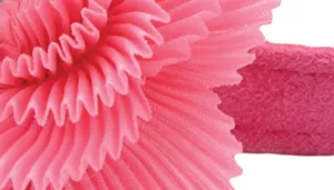 A swatch featuring a large, textured pink fabric flower attached to a pink strap. The flower is composed of multiple pleated layers that form a full bloom. The strap is made of smooth pink material with light stitching along the edges, complementing the soft decorative flower.