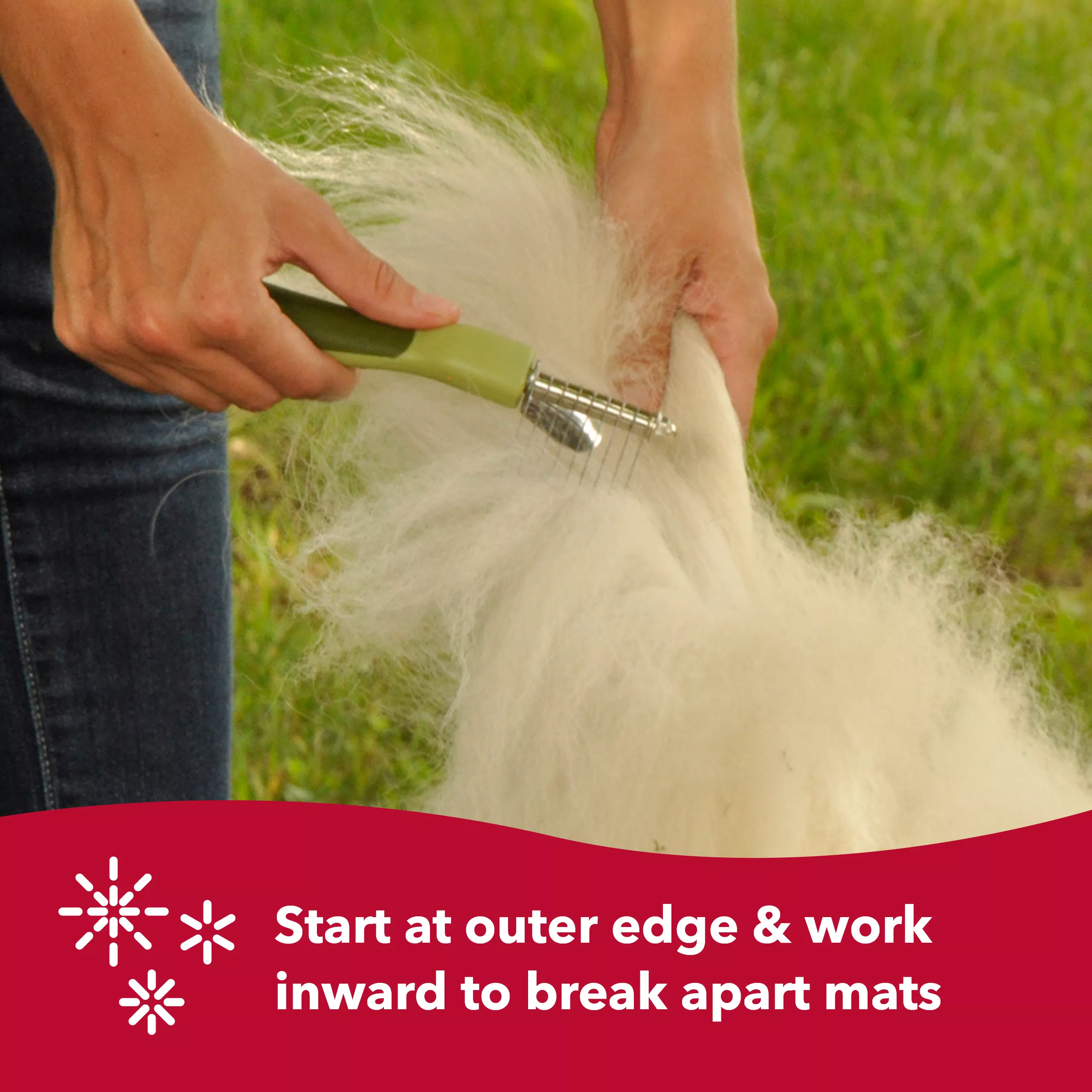 A lifestyle image featuring a person grooming long dog fur outdoors. The person holds a dog de‑matting comb with curved stainless‑steel blades and a light green handle with darker green grip accents. The comb is being drawn through light‑colored fur. Grass fills the background. A red banner appears along the lower portion with a white starburst‑style icon and the printed text “Start at outer edge & work inward to break apart mats.”