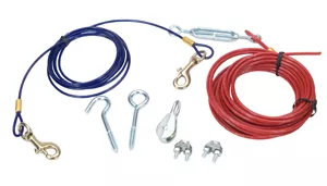 Two aerial dog run cables and assorted hardware are displayed against a plain white background. The cable on the left is dark blue with a smooth plastic coating and is loosely coiled. It has a silver metal swivel snap hook with a spring‑loaded clasp attached at one end. The cable on the right is red with a similar smooth plastic coating and is also loosely coiled, with a silver metal hook component attached. Below the cables are several hardware pieces, including silver metal U‑shaped hooks with threaded ends, a silver metal turnbuckle, cable clamps with screws, a screw eye, and a small metal connector. All items are arranged so that each component is clearly visible.
